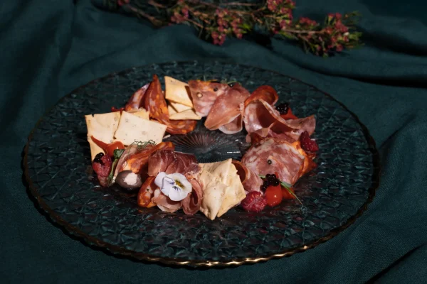 Rūkytų ir vytintų mėsyčių asorti lengvai rūkyta chorizo dešra, vytintas serano kumpis bei prieskoningas saliamis pateiktas su žolelių aliejumi, krekeriais ir traškiomis lazdelėmis